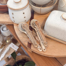 Load image into Gallery viewer, Collection of ceramic bowls and utensils on a wooden surface with a plant in the foreground.