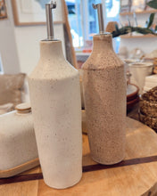 Load image into Gallery viewer, Two ceramic bottles with metal nozzles on a wooden table in a home setting.