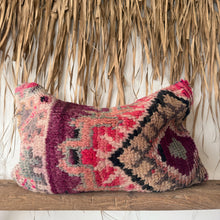 Load image into Gallery viewer, Decorative pillow with intricate patterns on a wooden shelf against a natural straw wall.