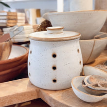 Load image into Gallery viewer, White ceramic jar with a wooden lid on a wooden surface with shelves in the background
