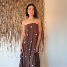 Load image into Gallery viewer, Woman wearing a brown strapless dress with white polka dots against a neutral wall.
