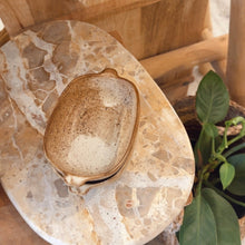 Load image into Gallery viewer, Round stone table with a decorative bowl on top, set against a wooden chair and plant.
